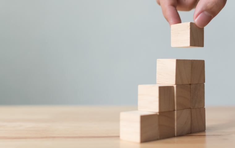 Hand arranging wooden blocks as steps