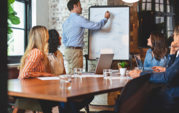 Office full of people watching a business presentation