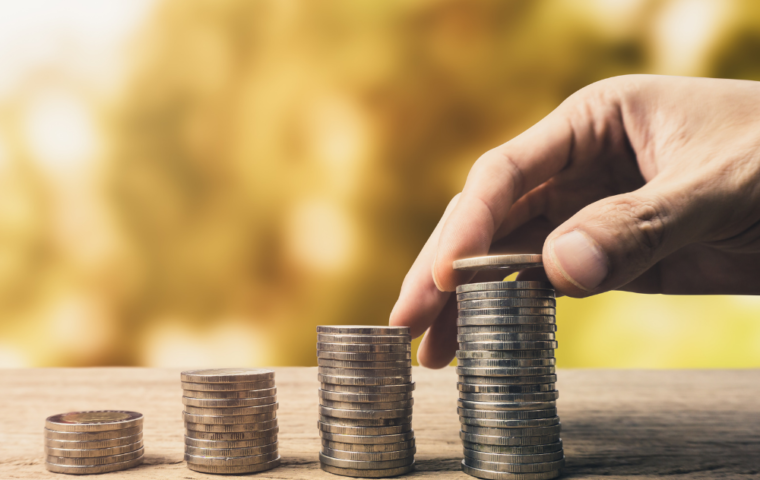 Raising Finance concept Male hand adding a coin to the top of a stack of coins