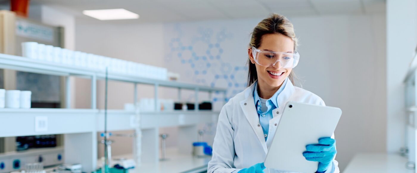 lab worker wearing safety goggles and working on tablet