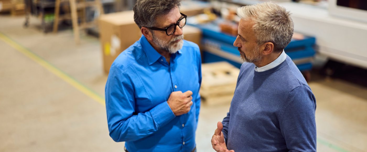 two warehouse workers discussing business in warehouse