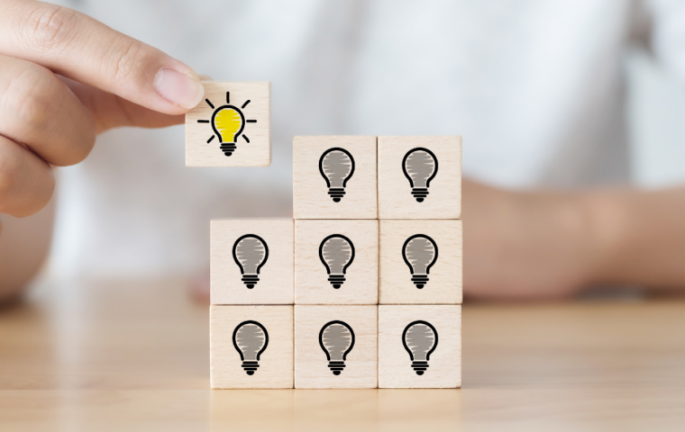 Hand picked wooden cube block with light bulb icon distributing the overall square shape