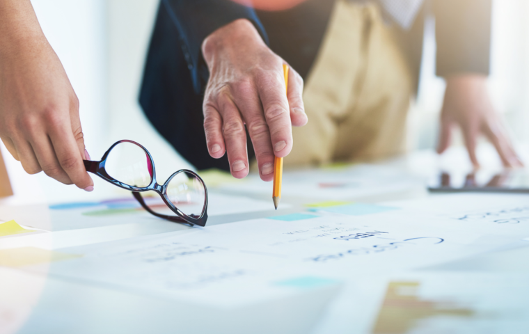 Employees pointing down at business plans on a table to scale business