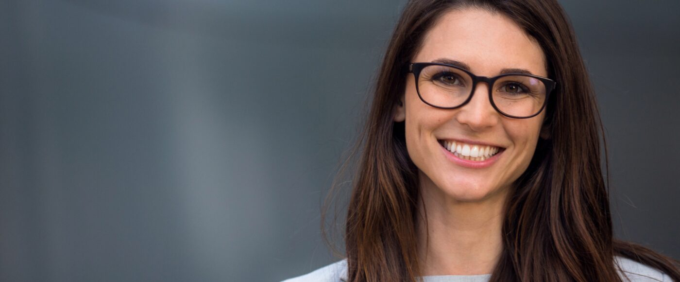 business professional wearing glasses smiling at camera with dark background