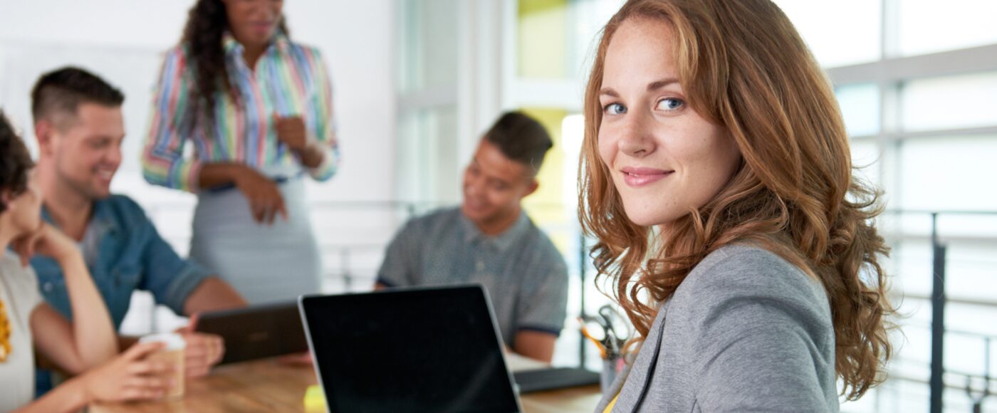 office worker looking at camera with project team in the background