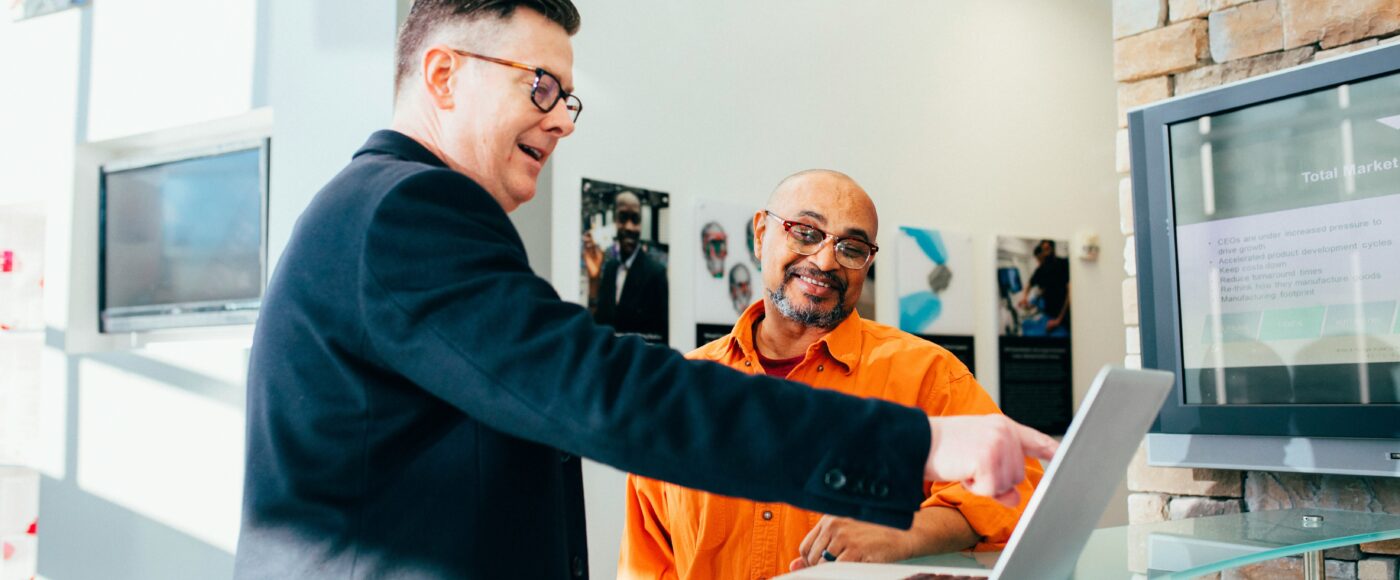 2 Business men looking happy pointing to a laptop
