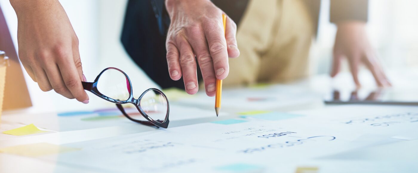 Employees pointing down at business plans on a table to scale business