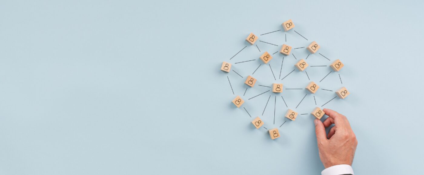 A hand adding a building block to a network of people