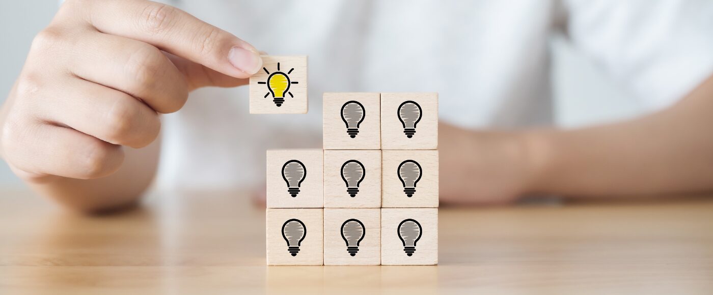 Hand picked wooden cube block with light bulb icon distributing the overall square shape