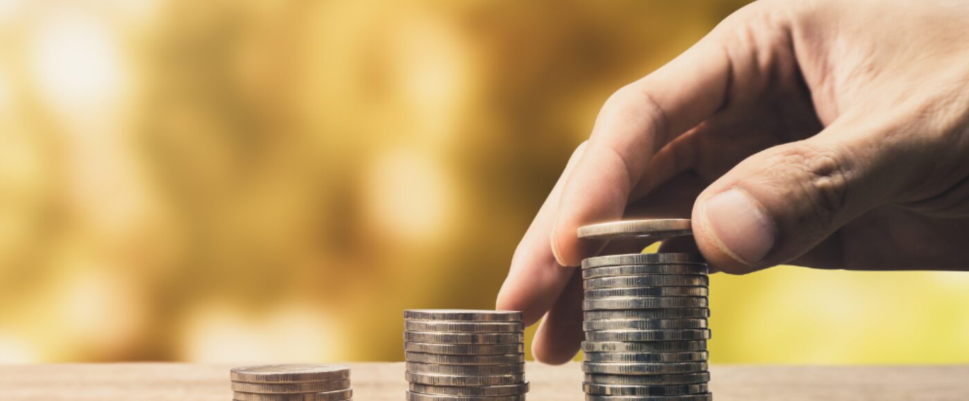 Male hand adding a coin to the top of a stack of coins