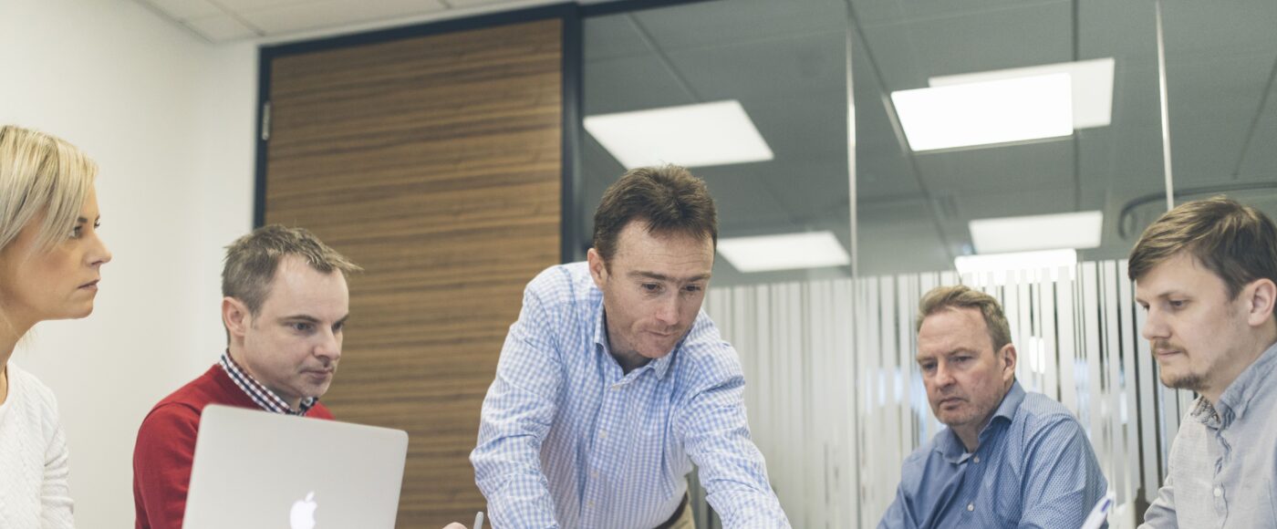 Acumen participants sitting around a meeting table planning using a laptop and pen and paper