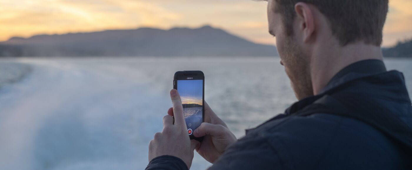 Man taking video of snow covered lake during sunrise